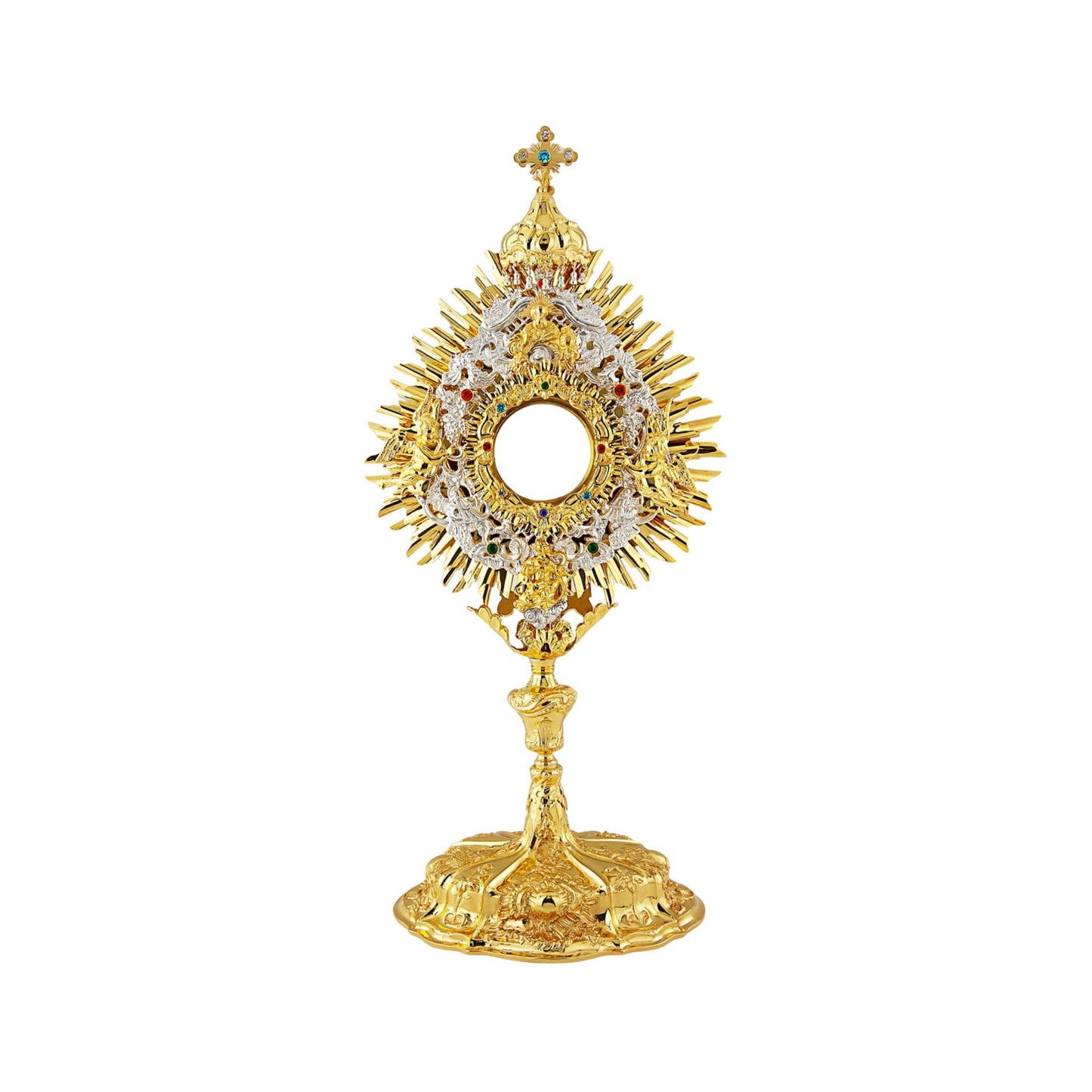 Richly adorned Baroque brass monstrance, 24-karat gold-plated with silver-plated accents. The glory consists of three layers: two sunbursts topped with a cross and a silver-plated wreath. The wreath features angel figures on either side of the luna case and God the Father sheltered with a canopy right above it. The luna case is surrounded by an ornamental design set with colorful stones. Highly decorated, sculpted node and base.