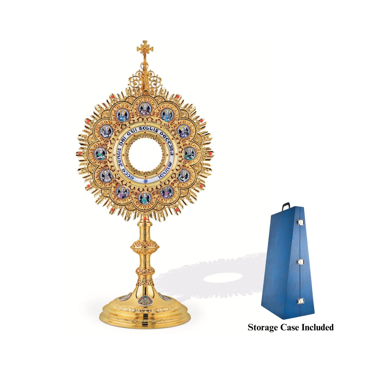 Brass monstrance, 24-karat gold-plated with red stones and enameled accents, inspired by German models from the late XIX and early XX centuries. The magnificent glory consists of a sunburst and a layer of ornate open filigrees with medallions depicting the Apostles. The gold-rimmed luna case has a blue-enameled Latin inscription: “Ecce Agnus dei Qui Tollis Peccata Mundi”. The stem and the node are decorated with fine filigrees. Medallions on the round base feature symbols of the Evangelists. All medallions