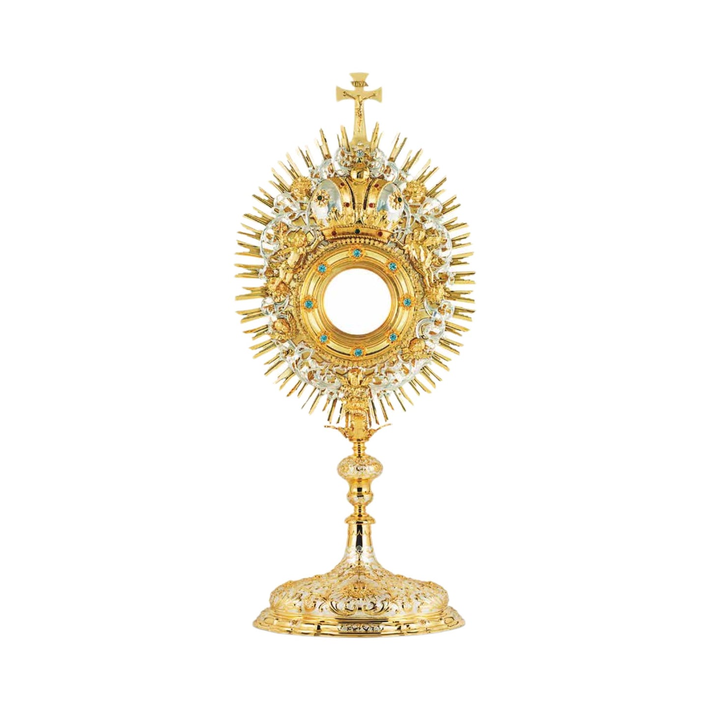 Baroque monstrance made of brass, 24-karat gold-plated with silver-plated accents. The luna case is encrusted with synthetic blue stones and surrounded by a decorative wreath with a crown and images of angels. The glory is sunburst-shaped and topped with a cross. The node and the base are adorned with rich ornamental patterns in two tones.