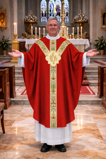 Priest in a red gothic liturgical vestment with IHS embroidery standing in a church.