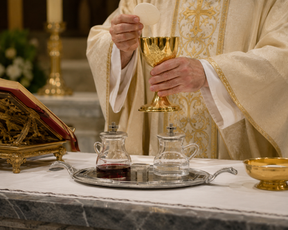 Priest in liturgical vestments holding a chalice with a cruet set crystal glass water and wine in silver finish.