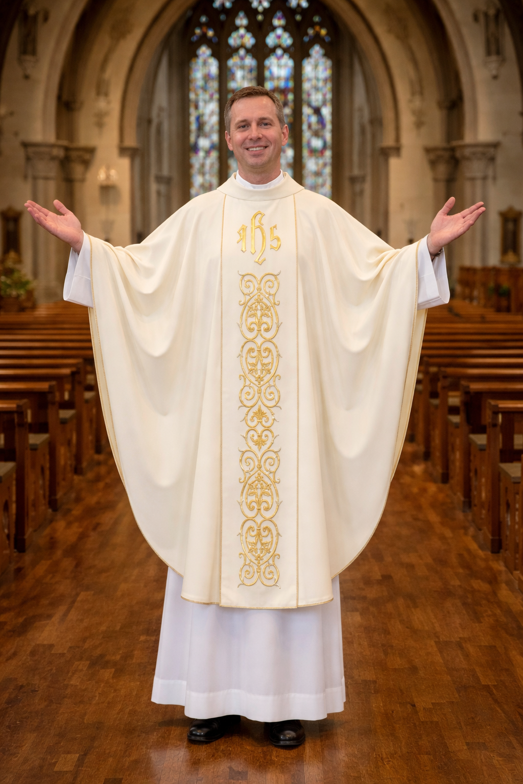 Priest in a white robe with gold embroidery standing in a church nave with stained glass windows.
