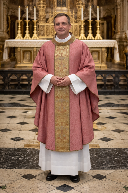 Priest in liturgical vestments standing in a church with altar and candles in the background