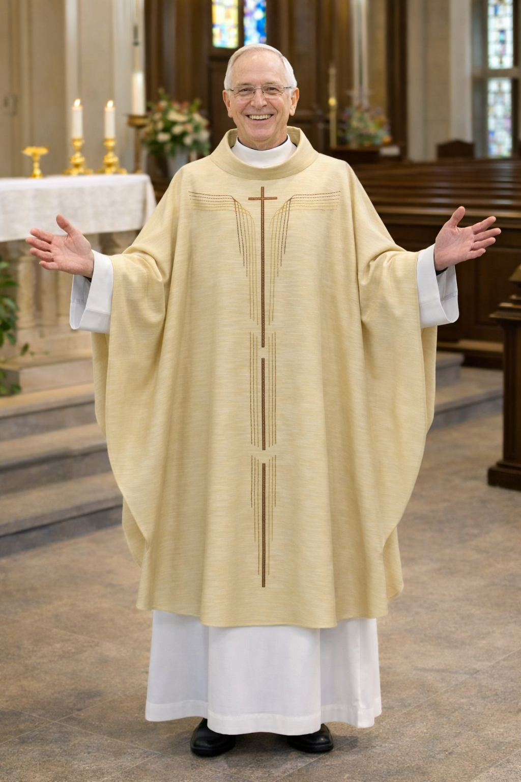 Priest in a beige liturgical vestment standing in a church with stained glass windows.