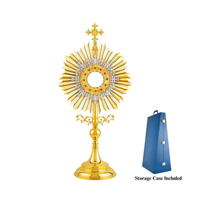 Traditional, sun-shaped monstrance made of brass, 24-karat gold-plated. The luna case is surrounded by a silver-plated floral wreath and a round decorative frame set with red stones. At the top of the monstrance there is a big cross with sculpted ornaments. The node and the base are finished in high gloss.
