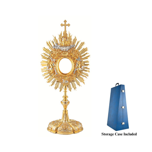 Baroque monstrance made of brass, 24-karat gold plated with silver plated accents. The glory consists of a sunburst topped with a cross and a decorative layer of floral ornaments around the luna case. God the Father and the Holy Spirit are placed at the top of the glory, while the Lamb of God is placed at the bottom. On either side of the luna case there is an angel figure. Both the node and the oval base richly adorned with floral ornaments and images of angels. The monstrance is coated with a protective l