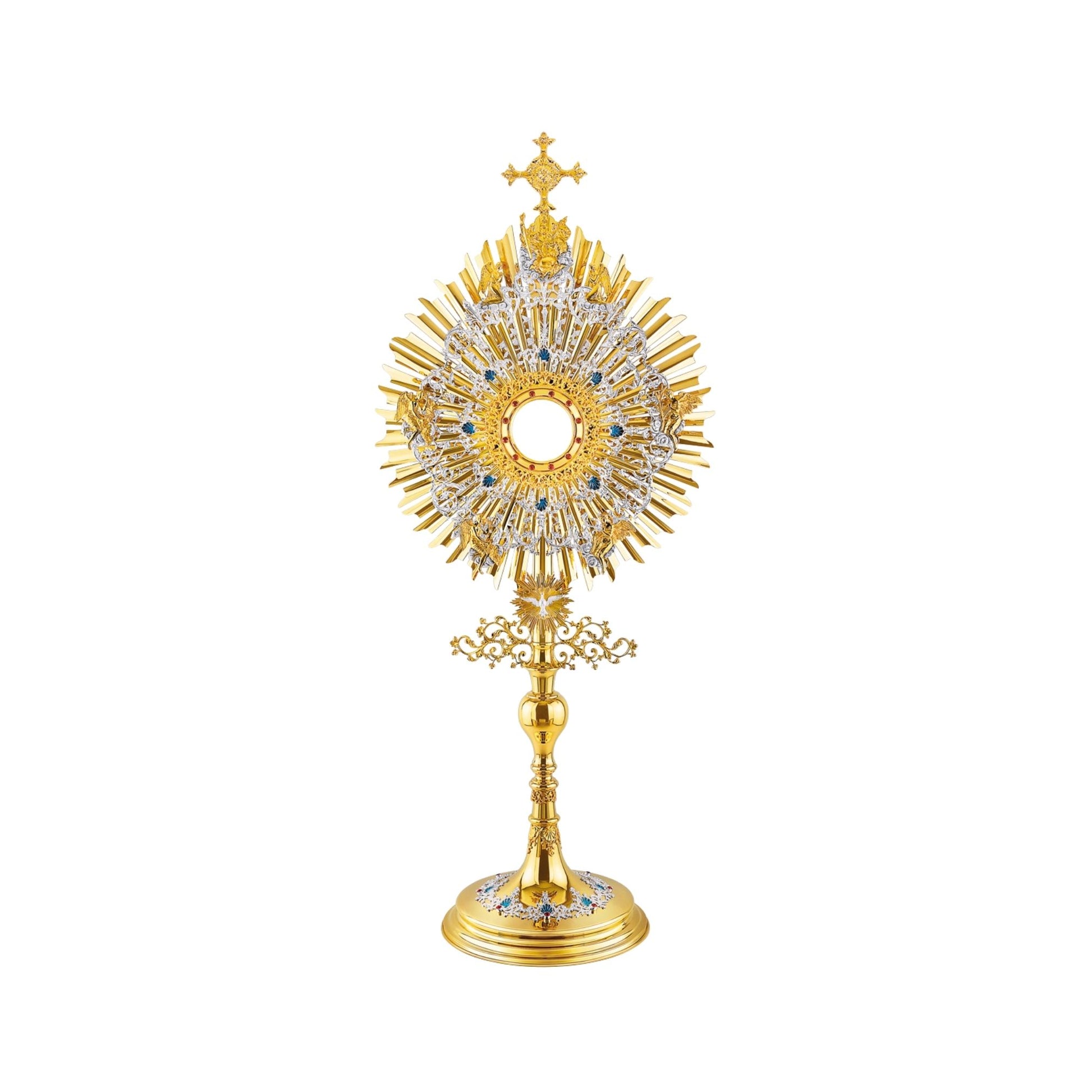 A large monstrance (height: 43-3/4") made of brass, 24-karat gold-plated with silver-plated and blue-enameled accents. The sunburst-shaped glory consists of three layers of rays and two silver-plated wreaths made of ornate floral scrollwork. The bigger wreath is adorned with figures of God the Father and Jesus at the top, and six angels around the luna case. The opening for the luna is gold-rimmed, filigreed and encrusted with synthetic red gemstones. 
