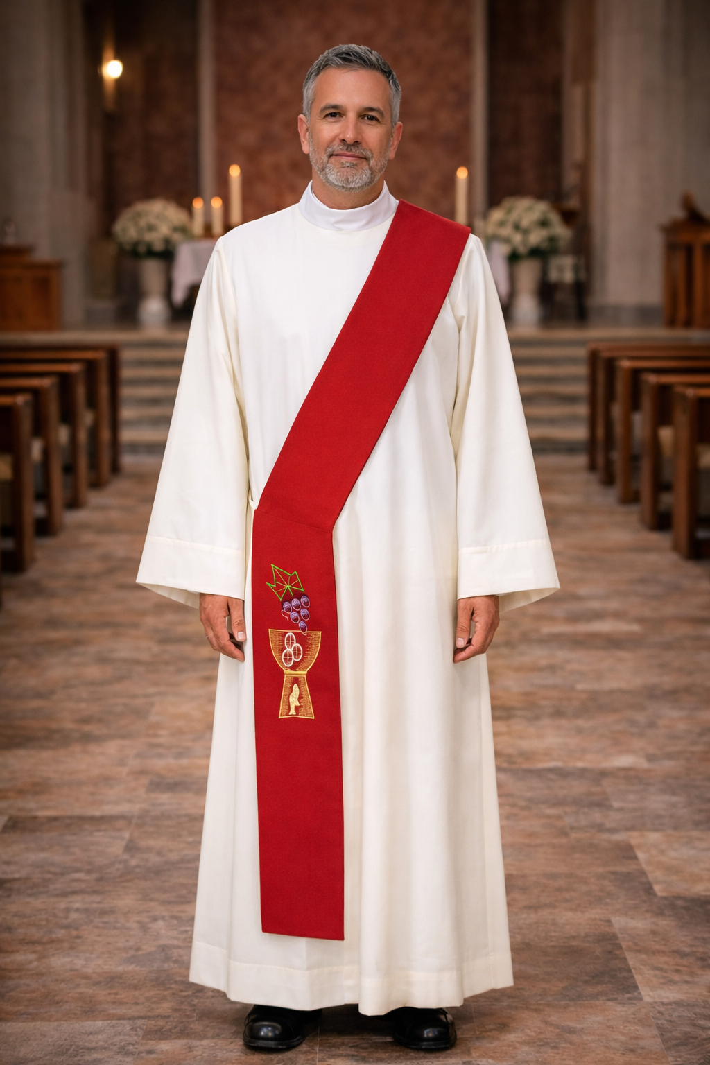 Deacon in white alb with red stole with chalice and grapes design standing in a church.