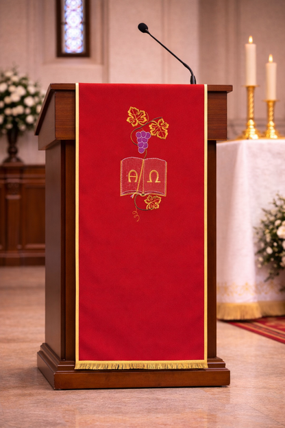 Red liturgical lectern cover with Alpha and Omega embroidery, grapevine design, and gold trim for church ambo or pulpit.