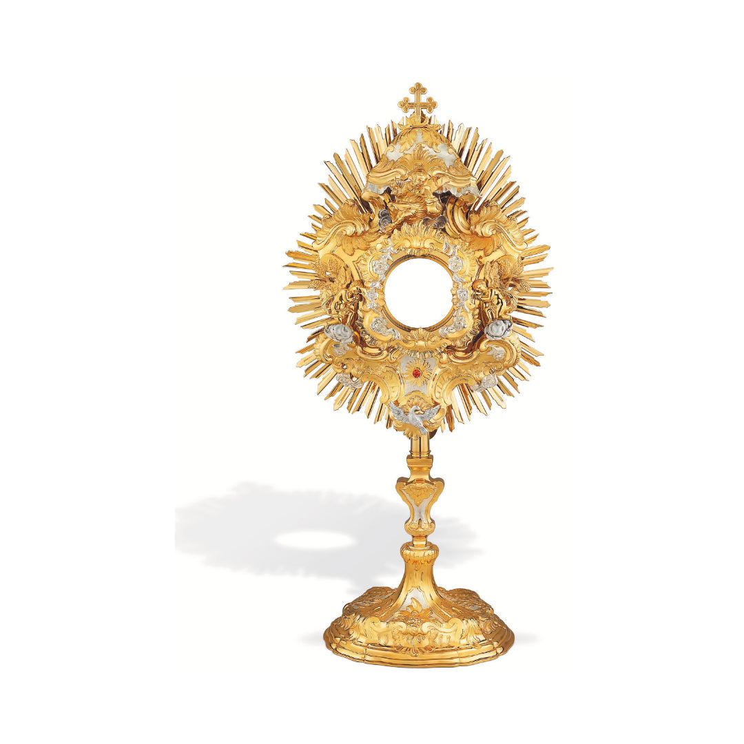 Richly adorned Baroque brass monstrance, 24-karat gold-plated with silver-plated accents. The sunburst is adorned with figures of God the Father, the Holy Spirit and angels. The node and the oval base are embellished with decorative patterns featuring grapevine and wheat motifs.
 
The monstrance is coated with a protective layer that shields it against humidity, fingerprints and other harmful factors. It also protects silver from darkening. 