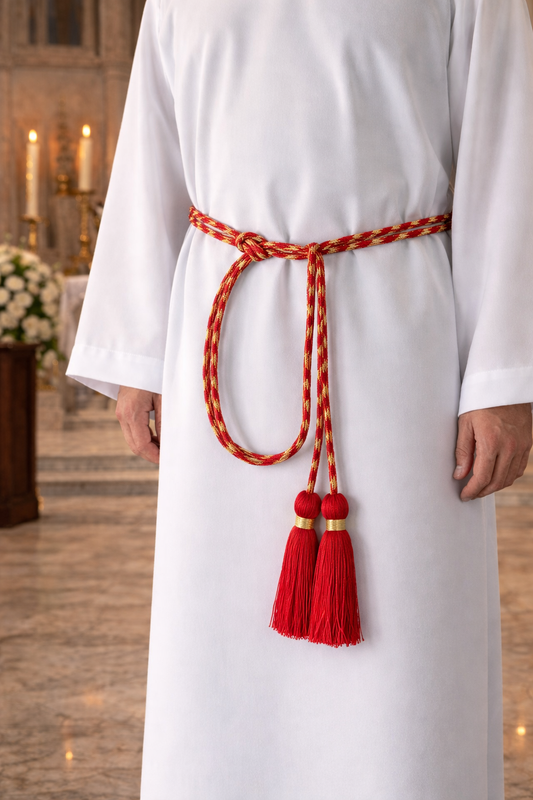 Clergy wearing a white alb with a decorative cinture featuring tassels in an indoor setting.